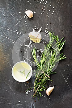 Spices, olive oil and herbs on a dark stone or slate table. Ingredients for cooking. Food background.