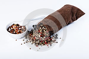 Spices in a sack, bulk spices in a porcelain dish, spoon on a white background.