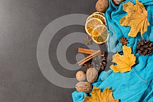 Spices, a scarf, nuts, dry leaves and oranges on a stone table. Autumn mood, a method to keep warm in the cold, copy space