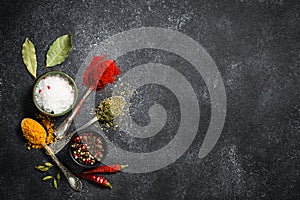 Spices, sea salt and pepper on black stone background.