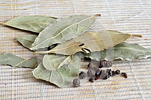 Bay Leaves Laurel Leaves with peas of black pepper on a light background