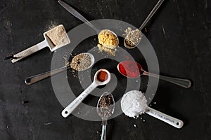 Spices in teaspoons on a dark surface