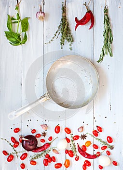 Spices, vegetables and frying pan with copy space on a wooden.