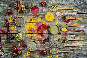 Spices in a wooden bowl, fresh tomatoes and hot red pepper lie on an old table