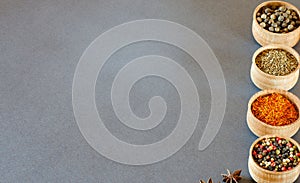 Spices in wooden bowls on a gray background