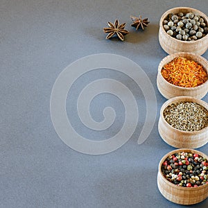 Spices in wooden bowls on a gray background