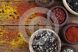 Spices in wooden bowls stand on an old wooden background. Free space