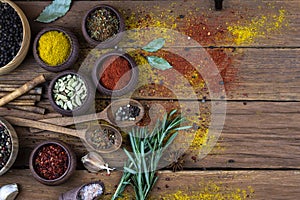 Spices in wooden bowls stand on an old wooden background. Free space