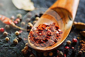 Spices in wooden spoon. Various Indian spices on black stone table. Spice and herbs on slate background. Cooking