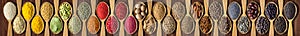 Spices in wooden spoons on black table. set of condiments and herbs for decorating website headers or packs with food