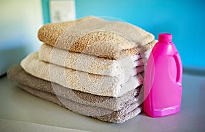 Spick and span. a bottle of detergent alongside a pile of folded towels.