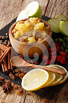 Spicy apple chutney with lemon and spices close-up in a bowl. vertical