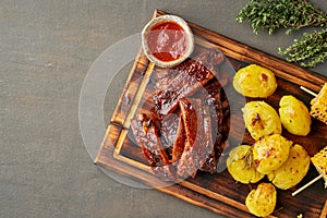 Spicy barbecue pork ribs, corn ears and crushed smashed potatoes. American Cuisine. Top view, copy space