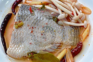 Spicy boiled Tilapia or mango fish tail with shimaji mushroon in tom yum soup on plate