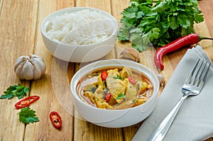 Spicy chicken breast in yellow curry sauce with garlic and chili  pepper with boiled rice in a bowl.
