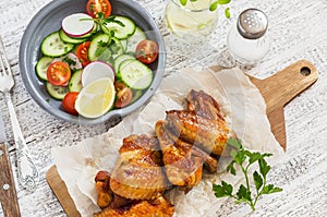 Spicy chicken wings and fresh vegetable salad