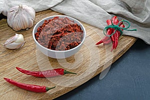 Spicy chili on a dark background in ceramic plates on a wooden Board, flatlay. Used as an ingredient for harissa, ajika, muhammara