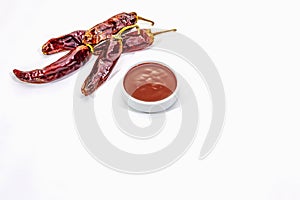 Spicy chili sauce in bowl isolated on white background. Different varieties of dry hot peppers, main ingredient for preparation.