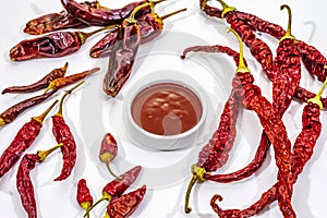 Spicy chili sauce in bowl isolated on white background. Different varieties of dry hot peppers, main ingredient for preparation.