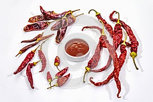 Spicy chili sauce in bowl isolated on white background. Different varieties of dry hot peppers, main ingredient for preparation.
