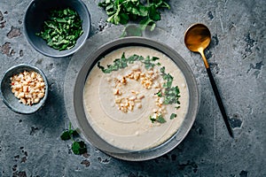 Spicy and creamy cauliflower and coconut soup with cilantro and macadamia nuts photo