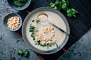 Spicy and creamy cauliflower and coconut soup with cilantro and macadamia nuts photo