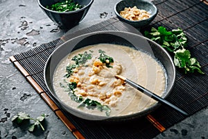 Spicy and creamy cauliflower and coconut soup with cilantro and macadamia nuts photo