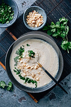 Spicy and creamy cauliflower and coconut soup with cilantro and macadamia nuts photo