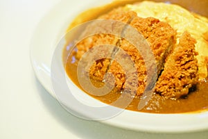 Spicy crispy pork cutlet omelet curry serve on white dish.