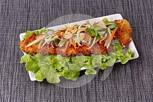 Spicy deep-fried Dolly`s fish salad with roll green mango.