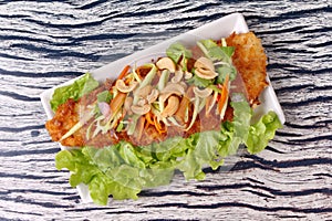 Spicy deep-fried Dolly`s fish salad with roll green mango.