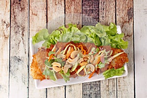 Spicy deep-fried Dolly`s fish salad with roll green mango.