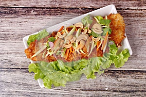 Spicy deep-fried Dolly`s fish salad with roll green mango.
