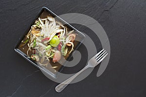 Spicy delicious papaya salad on black tile