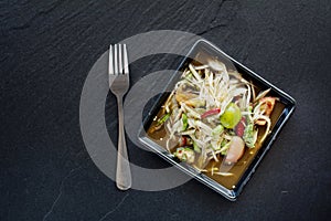 Spicy delicious papaya salad on black tile