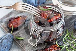 Spicy dried plum in a jar and a fork close-up.