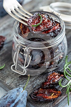 Spicy dried plum in a jar and a fork close-up.