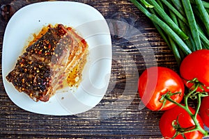 Spicy fried brisket, with fresh tomatoes and green onion feathers on a dark wooden background