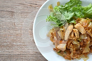 spicy fried large rice noodles with chicken and slice lettuce on plate