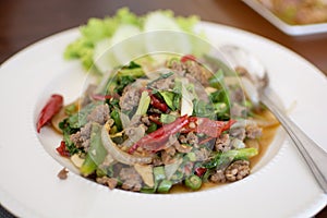 Spicy fried pork with basil leaves in white dish, Thai menu