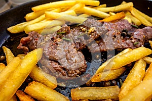 Fried spicy pork steaks with french fries in pan