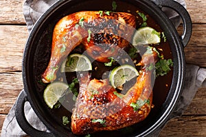 Spicy fried tamarind chicken quarter leg with lime close-up in a frying pan. horizontal top view