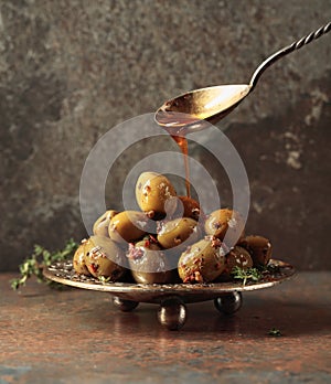 Spicy green olives are poured with olive oil with spices
