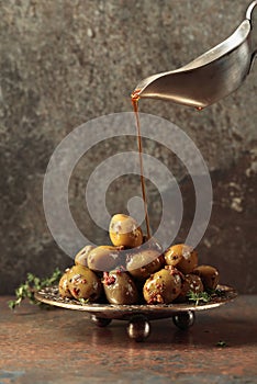 Spicy green olives are poured with olive oil with spices