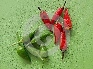 Spicy green and red chillies, the greens are fresh, the reds are dry and poorly preserved, all on a green background with small dr