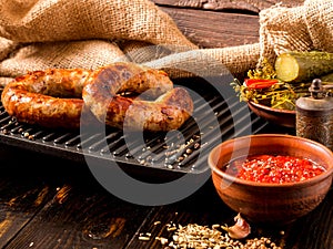 Spicy homemade sausages pork and beef sausages, on a wooden background, with sauce, spices and pickled cucumber . Template in