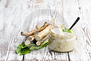 Spicy horseradish sauce in small glass jar on wooden table