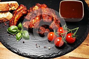 Spicy hot grilled spare ribs from a summer BBQ served with fresh tomatoes on an vintage cutting board