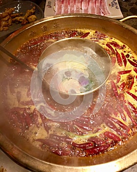 Spicy hot pot steaming with red pepper floating in