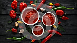 Spicy hot sweet chili sauce with mix of chilli pepper, garlic and tomatoes on rustic wooden background